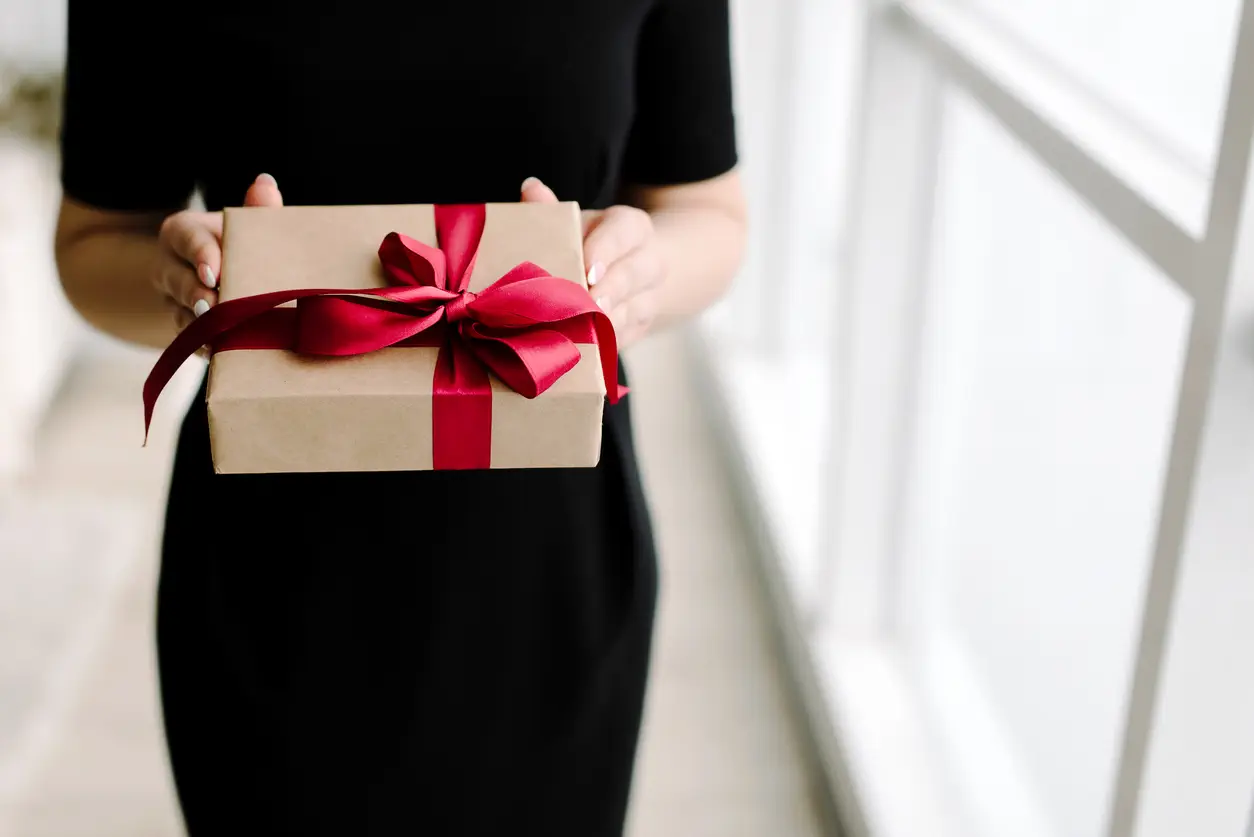 woman-giving-gift-wrapped-up-with-a-red-bow