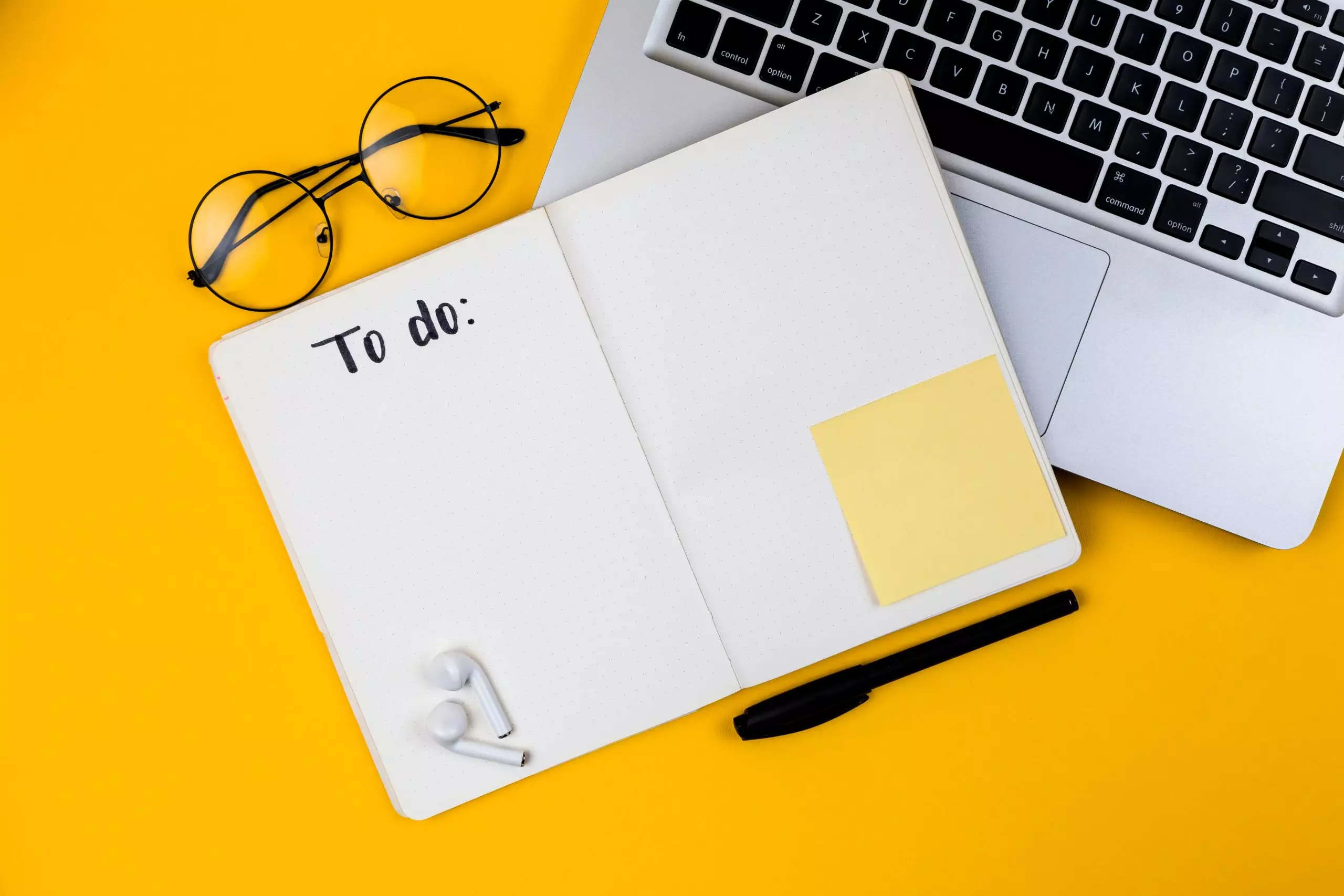 yellow-background-with-laptop-glasses-pen-and-notebook-with-to-do-list